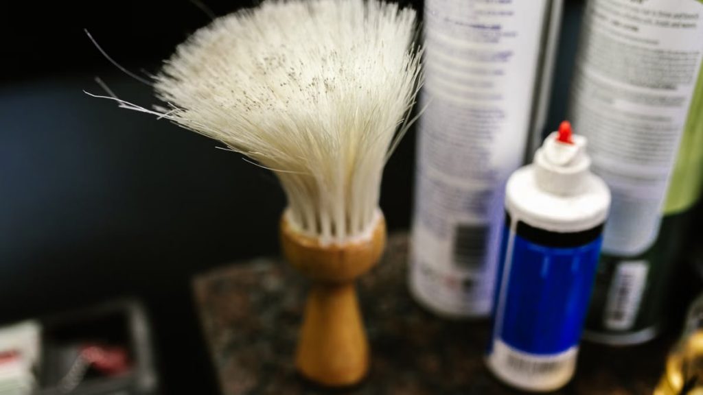 Close-up of a wooden handle barber neck duster in a barbershop setting.
